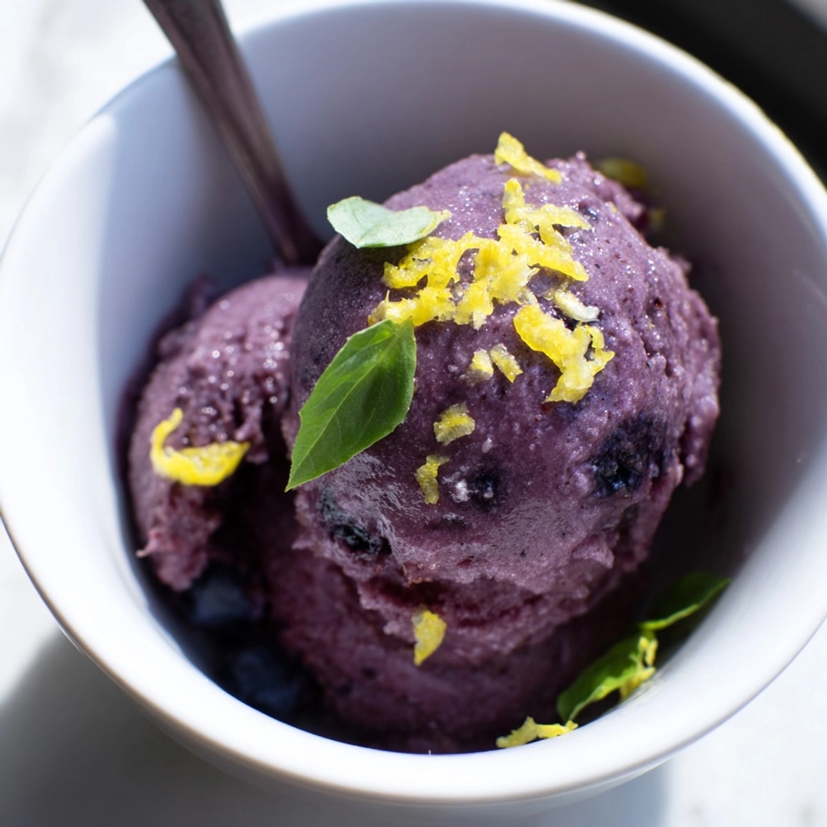 Freshly churned Blueberry & Basil Lemonade Sorbet glistens, ready to scoop on a hot day.