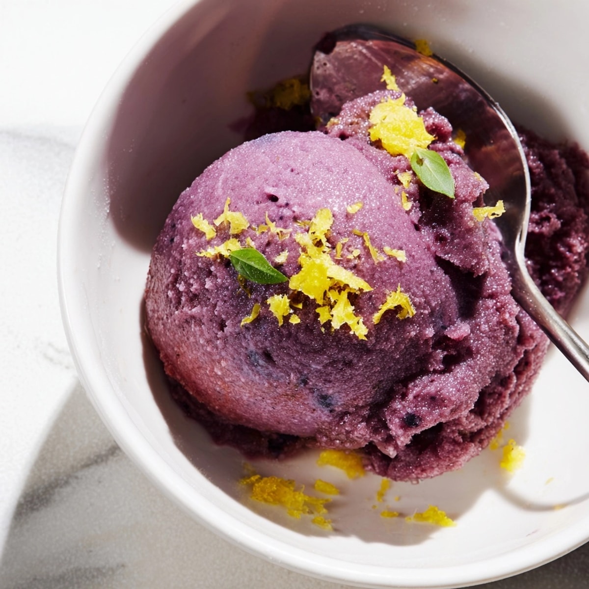 Swirls of purple and green Blueberry &amp; Basil Lemonade Sorbet in a metal ice cream maker.