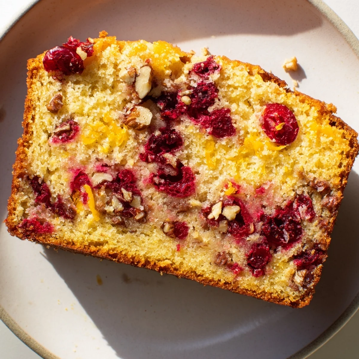Close-up of moist Cranberry Orange Bread, bursting with orange zest and ready to serve.
