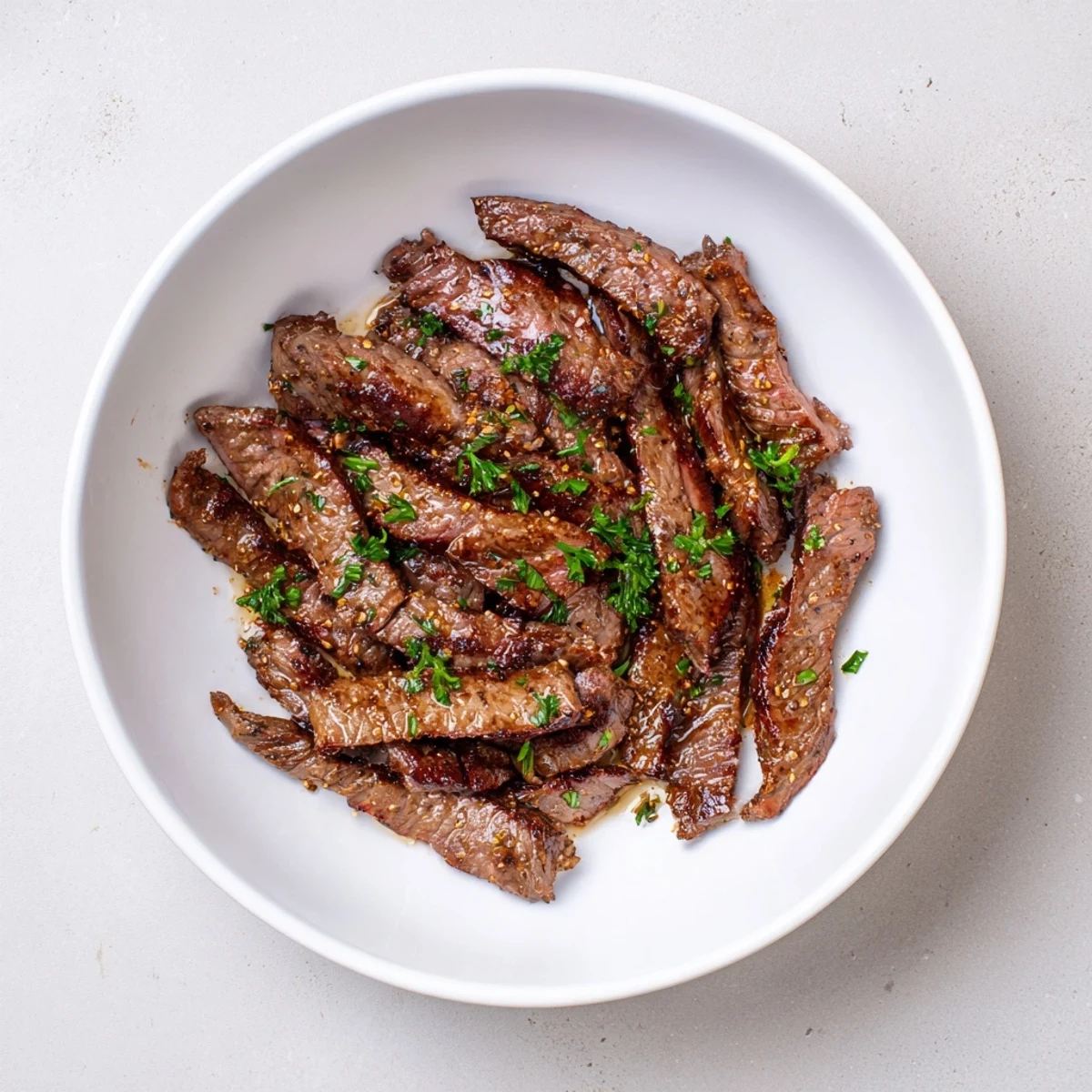 Perfectly seared cut beef, garnished with fresh parsley and ready for serving with lemon wedges.