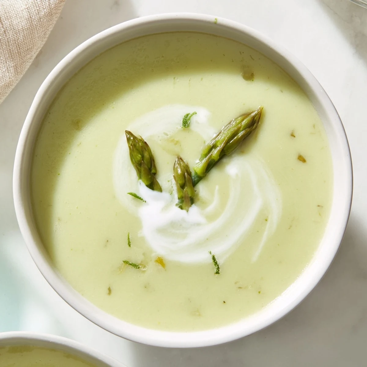 Velvety smooth creamy asparagus soup, garnished with fresh chives, a comforting spring meal.