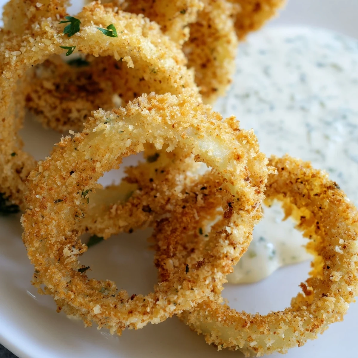 Stack of panko-crusted Crispy Baked Onion Rings with Ranch Dressing dipping sauce.