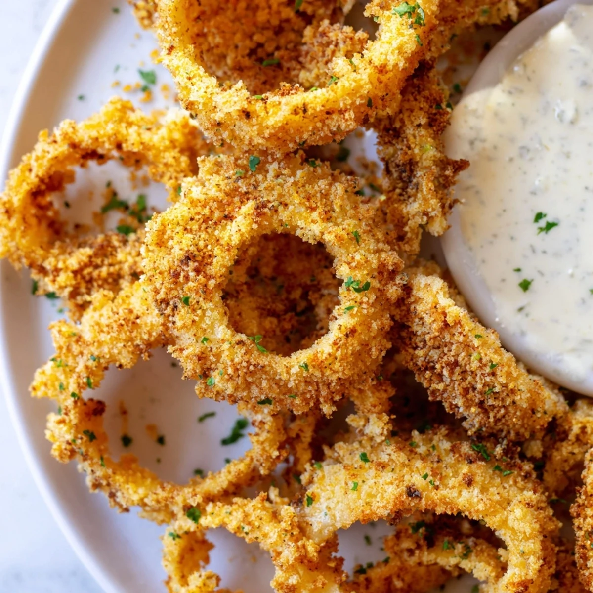 Freshly baked Crispy Baked Onion Rings with Ranch Dressing served hot on parchment.