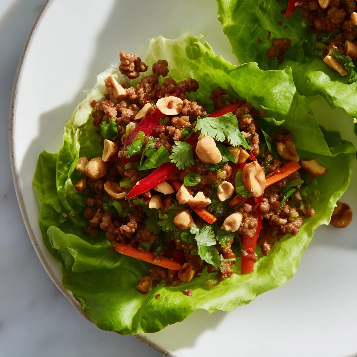 Sizzling savory ground beef mixture for Beef Lettuce Wraps with Peanuts, topped with chopped peanuts and a squeeze of fresh lime.