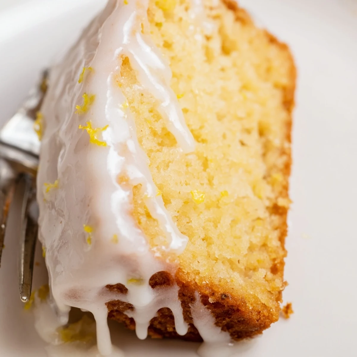 Freshly baked Lemon Loaf with glaze dripping down the sides on a rustic wooden board.