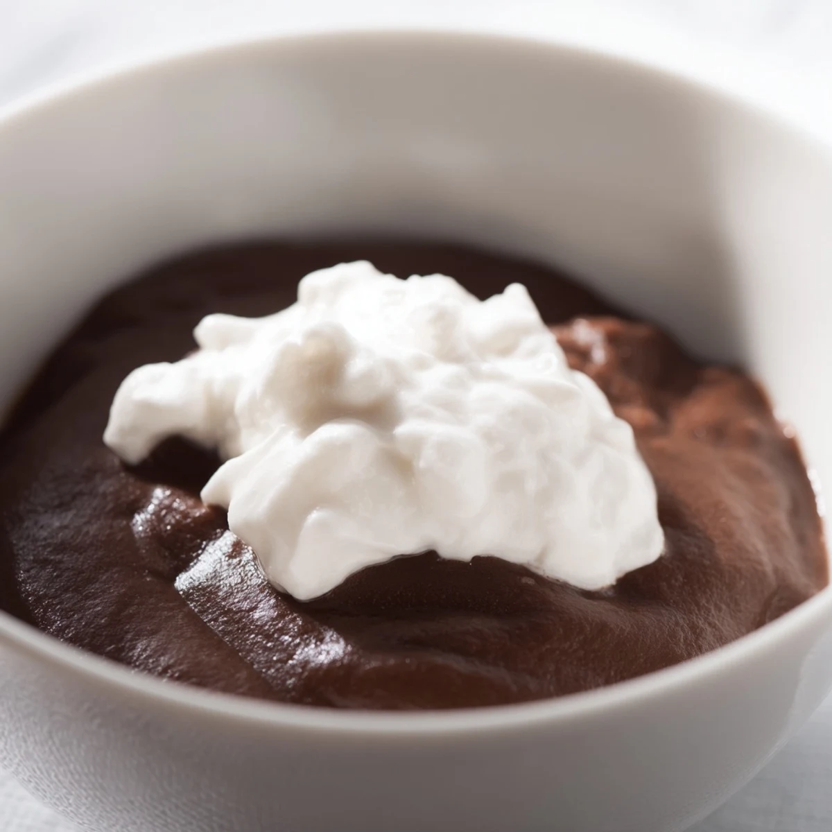 Luscious chocolate pudding dessert topped with whipped cream and cocoa powder, served in individual ramekins.