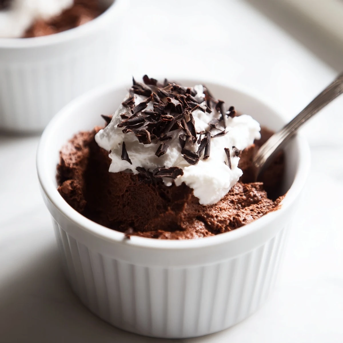 Chocolate Mousse with Whipped Cream layered in a glass, with chocolate shavings and a spoon ready to serve.