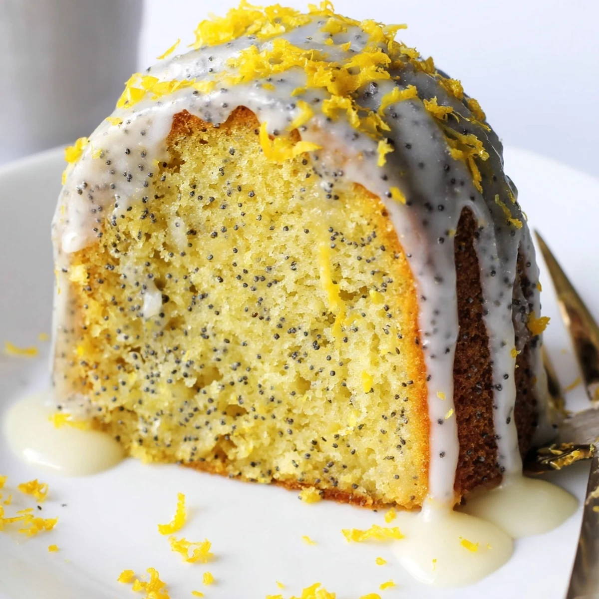 This moist Lemon Poppy Seed Bundt Cake is dusted with powdered sugar and served on a white cake stand.