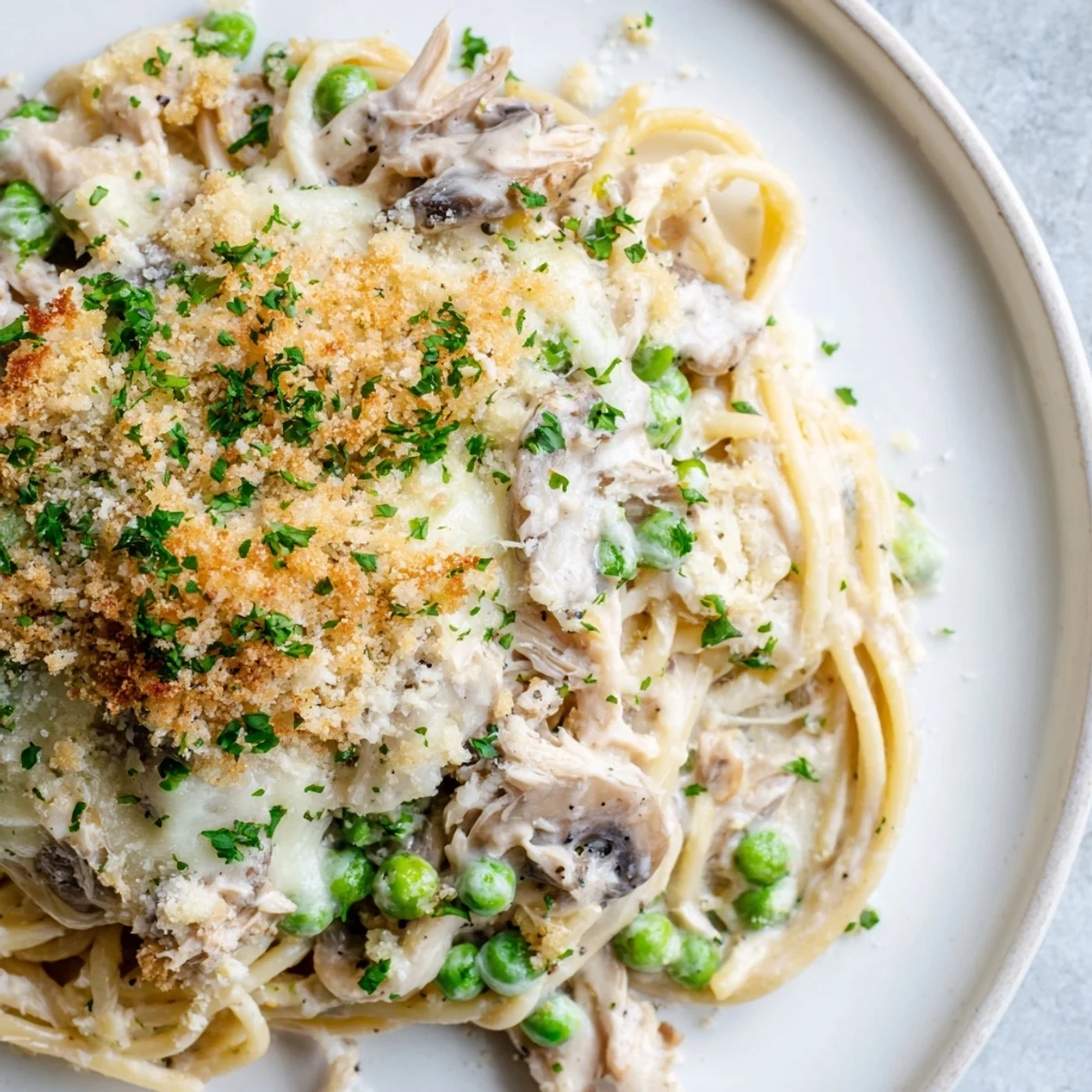 Serving dish of baked Turkey Tetrazzini casserole with golden cheese crust and herbs.