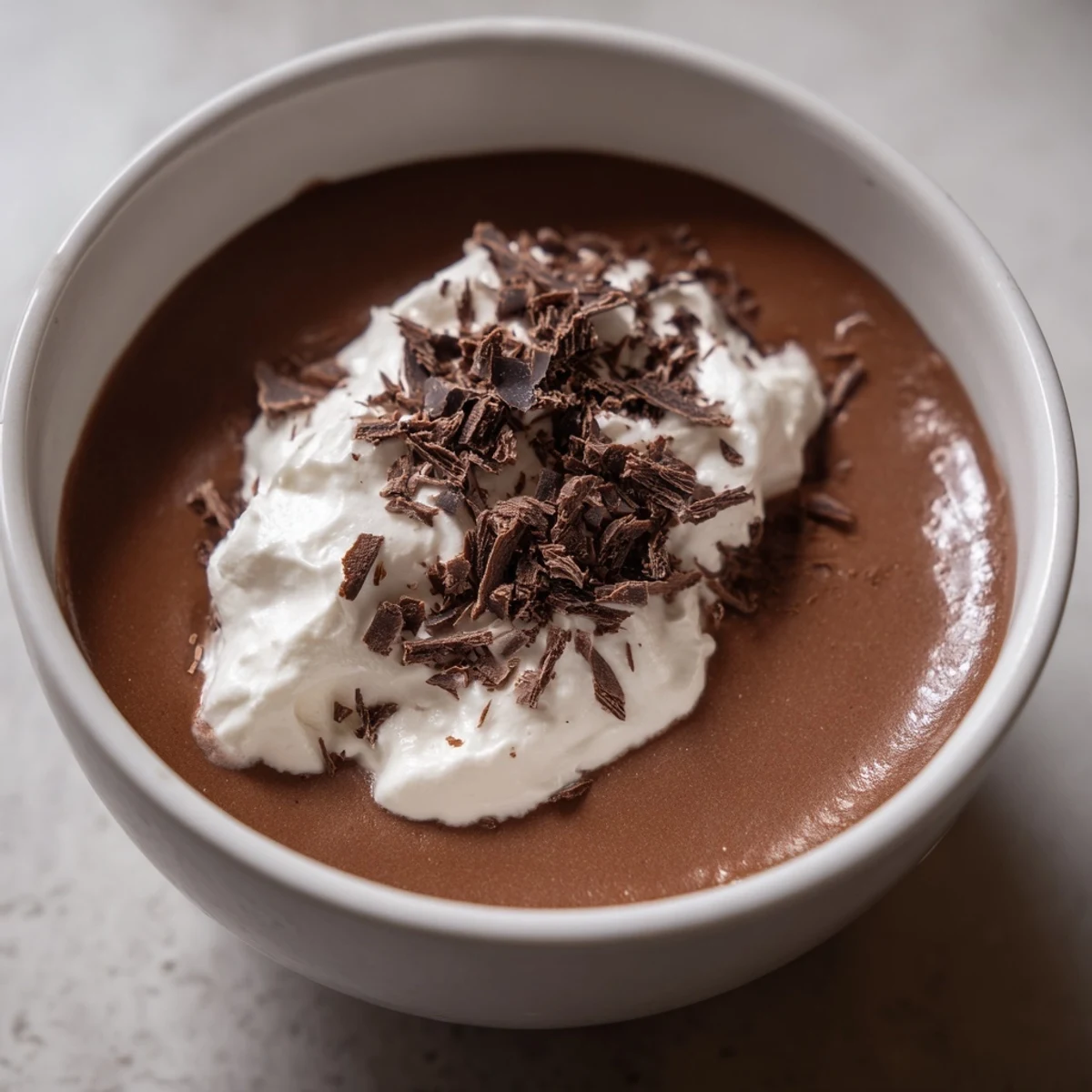 Four elegant dessert glasses filled with creamy Chocolate Mousse with Homemade Whipped Cream, garnished with fresh raspberries.
