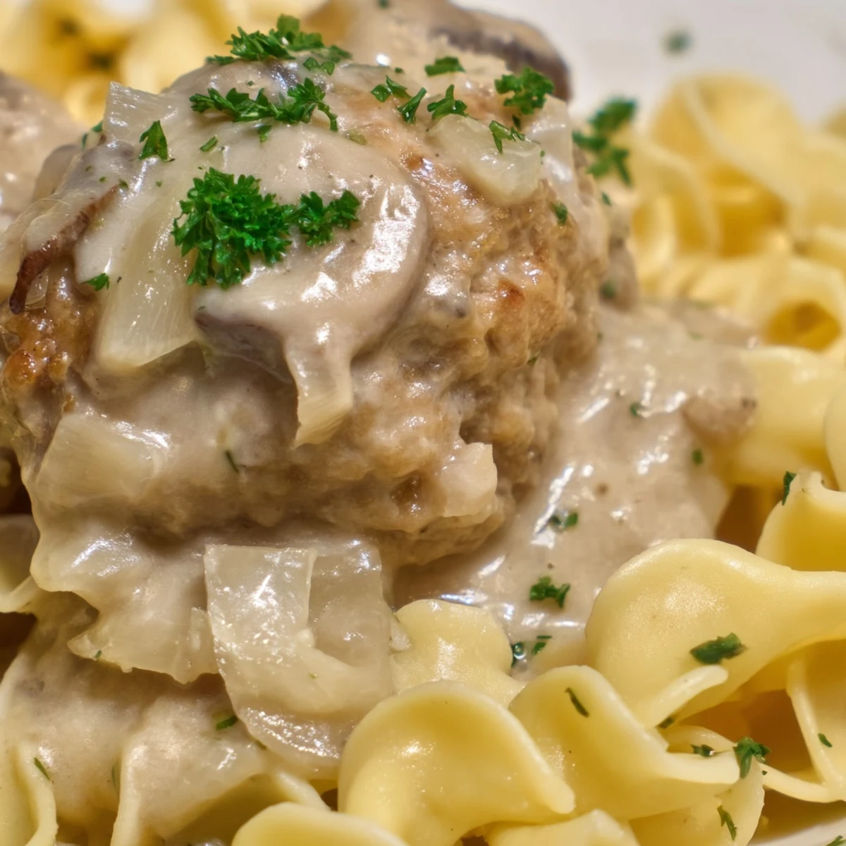 Golden brown turkey meatballs coated in creamy mushroom stroganoff sauce over tender egg noodles garnished with fresh parsley.