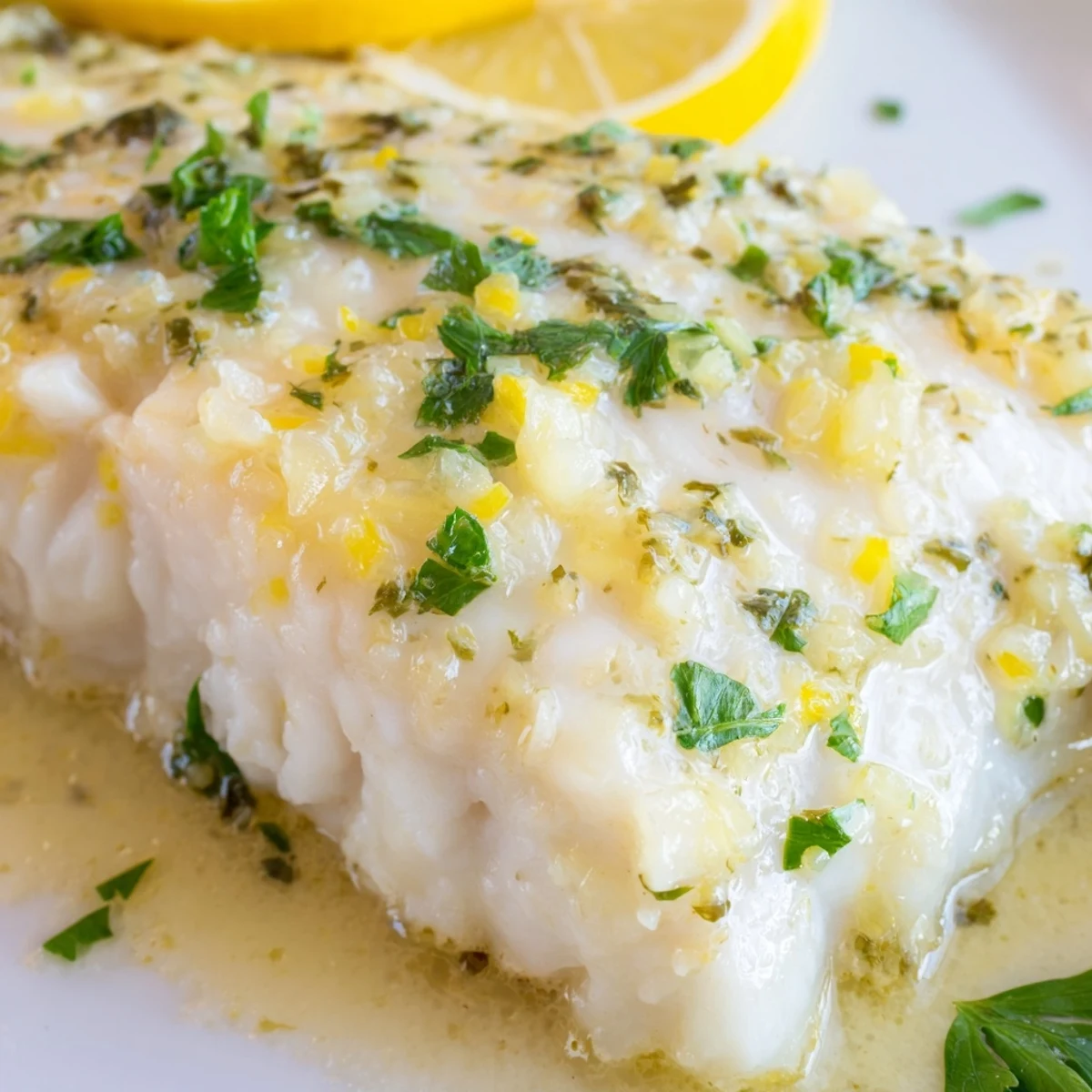 Golden-brown Baked Halibut with Lemon Butter served on a white plate, garnished with fresh parsley and lemon slices.