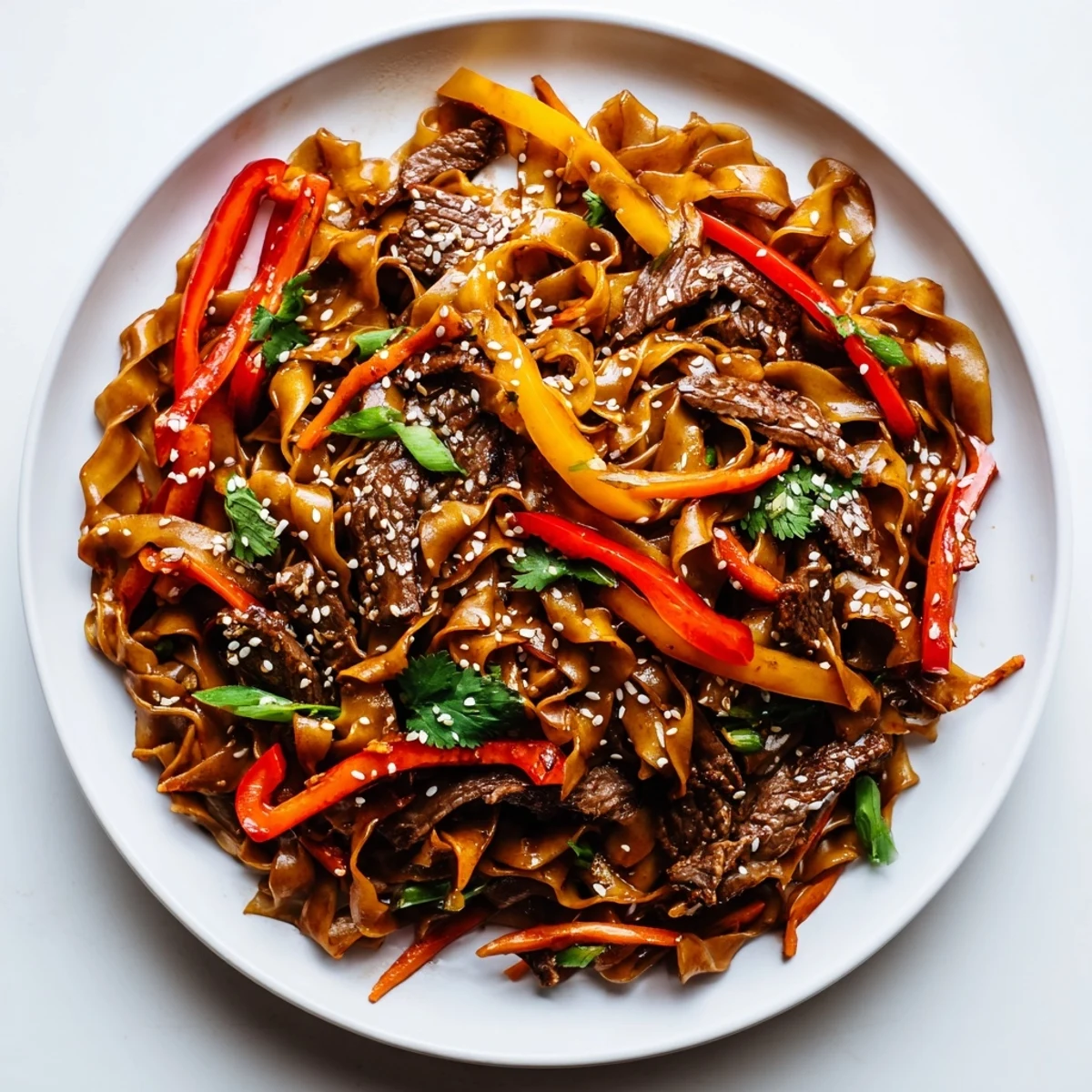 Close-up of sizzling Spicy Beef Stir Fry with Noodles, featuring tender beef, crisp red bell peppers, and snap peas in a glossy, savory sauce. 