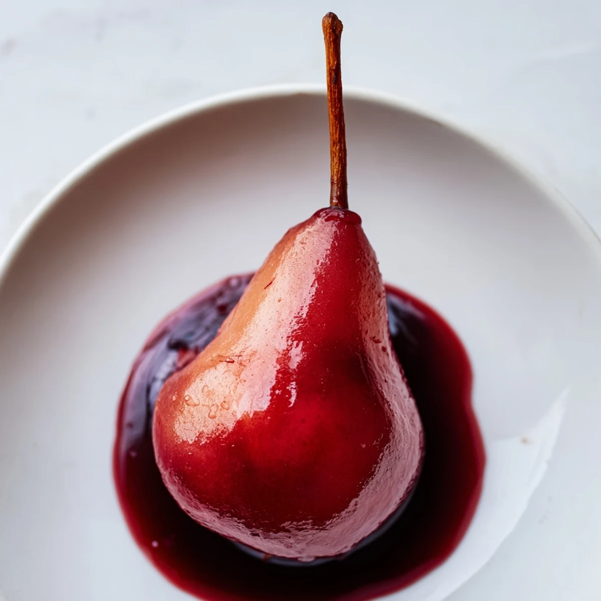 Four elegant Bosc pears glistening with a sweet grape juice reduction, infused with cinnamon and vanilla for a romantic dessert.