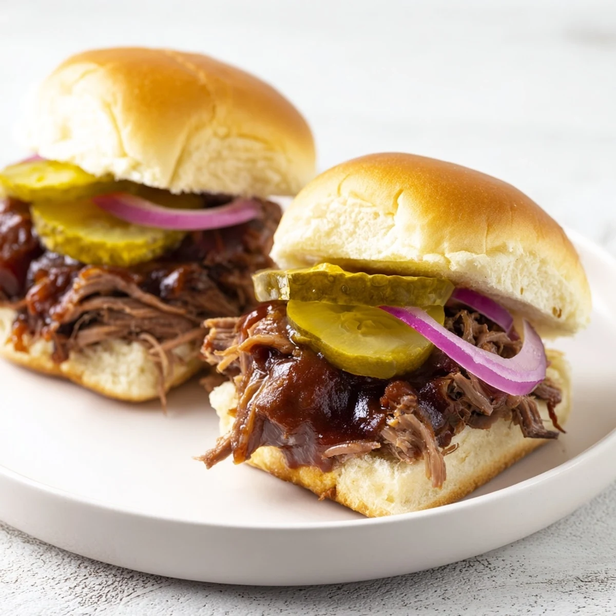Homemade pulled beef sliders featuring juicy shredded meat, pickles, and onions, ready to serve at a casual party.