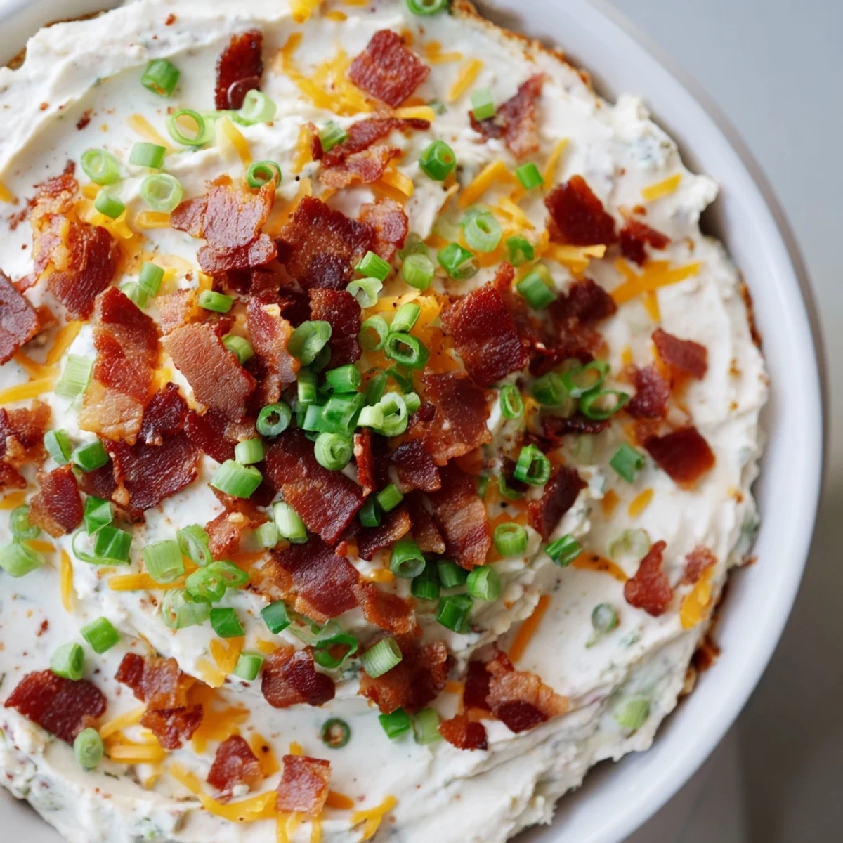 Creamy Loaded Baked Potato Dip garnished with fresh chives, bacon, and shredded cheddar, served alongside crispy kettle-cooked potato chips for dipping.  