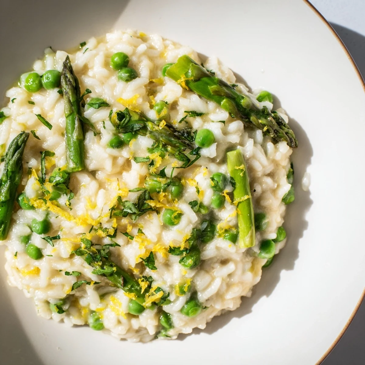 Creamy Spring Pea and Asparagus Risotto in a white bowl, garnished with fresh parsley and grated Parmesan.