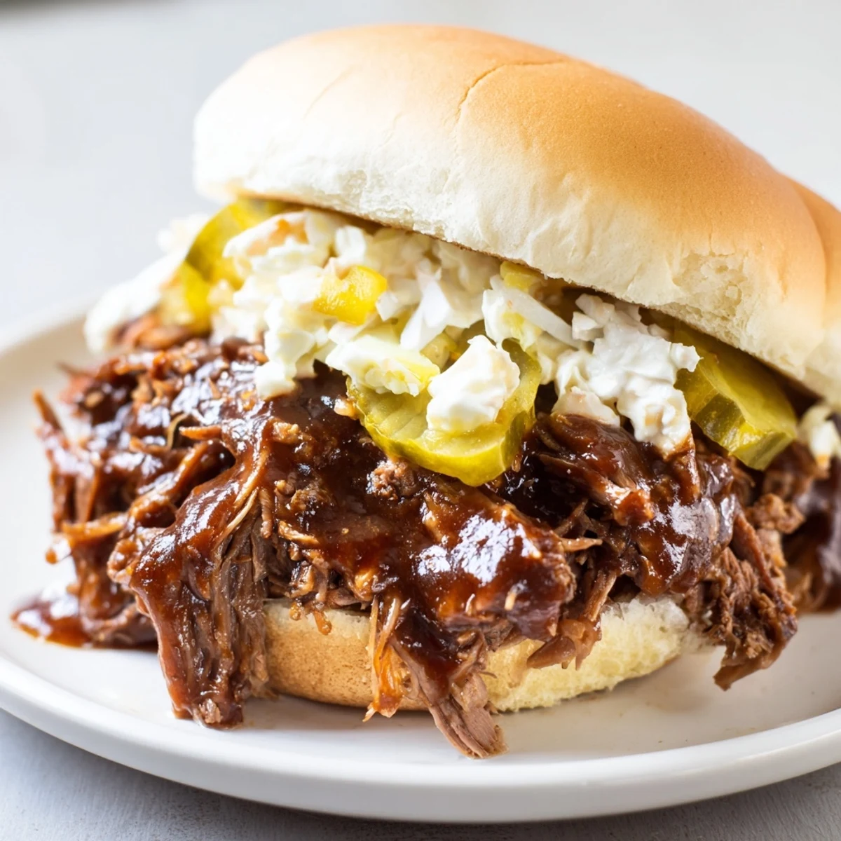 Slow Cooker Pulled Beef Sandwiches displayed on a rustic plate, juicy barbecue beef spilling over the edges alongside a side of golden fries.