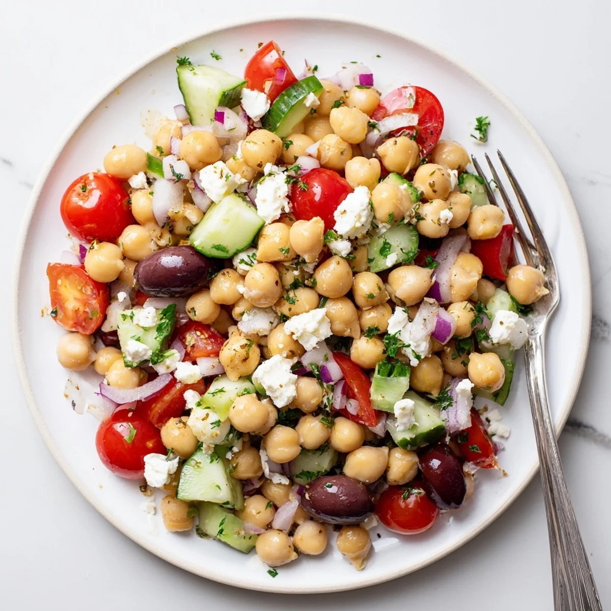 Colorful Mediterranean Chickpea Salad featuring crumbled feta, diced cucumbers, and a zesty lemon-oregano dressing for summer gatherings.