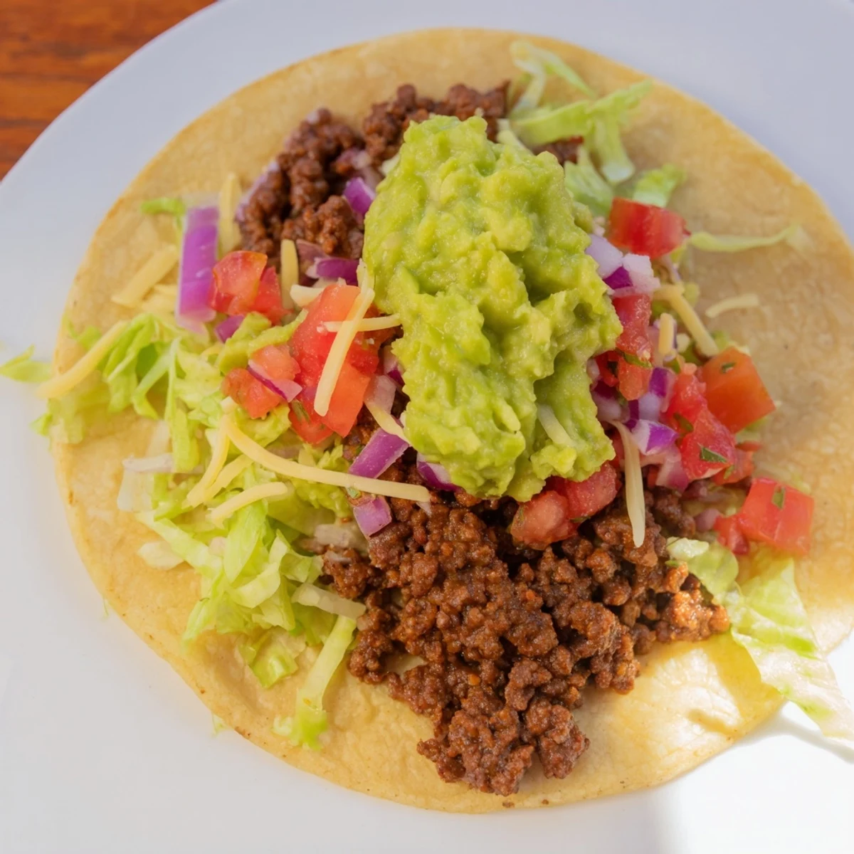 A plated serving of Beef Tacos with Homemade Salsa and Guacamole with lime wedges and extra salsa on the side.