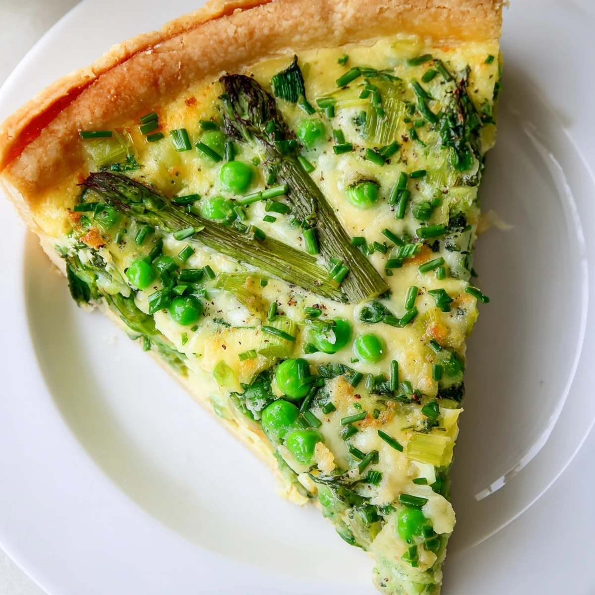 A freshly baked Spring Vegetable Quiche with Crust, featuring golden pastry and a custard filled with asparagus and peas.