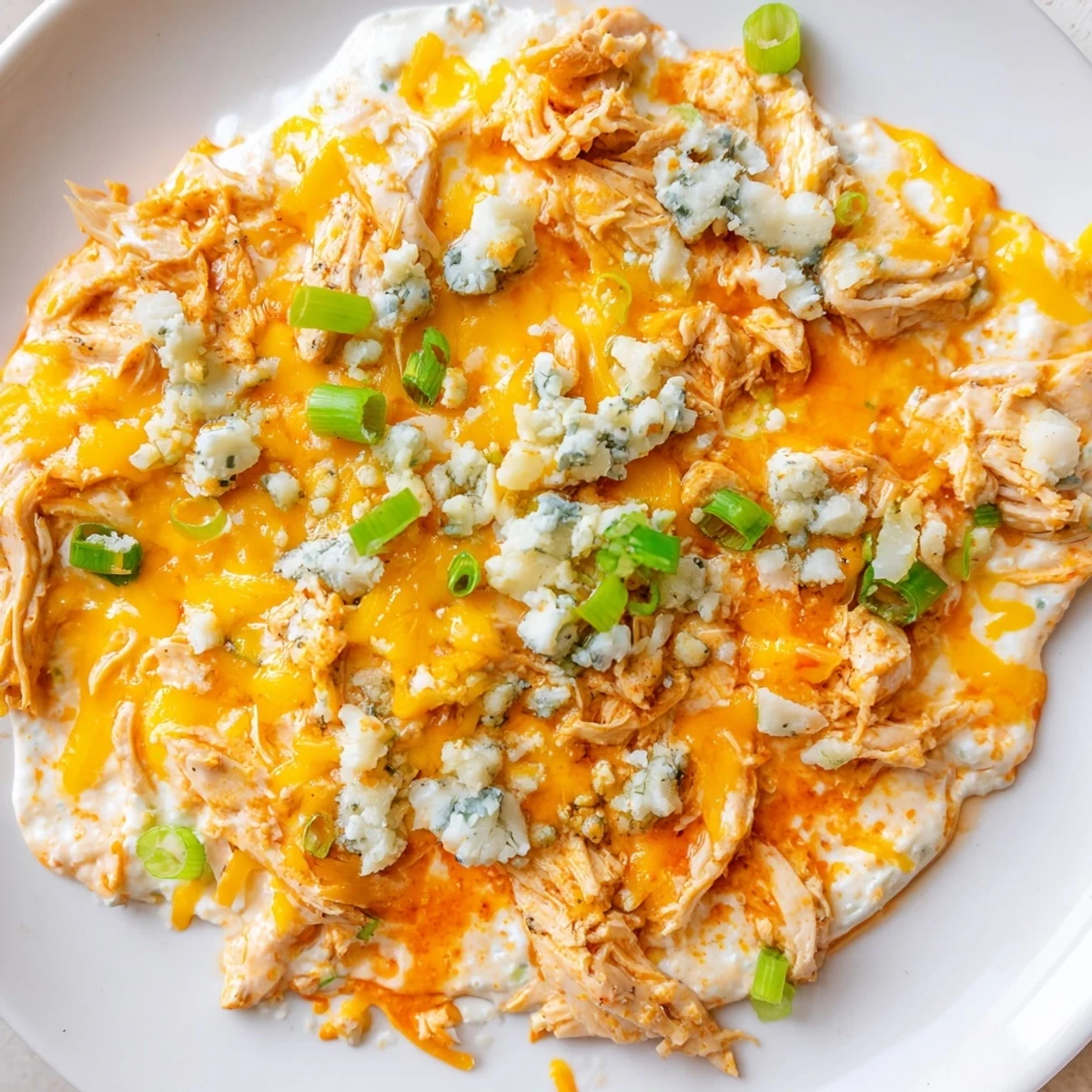 Freshly baked Keto Buffalo Chicken Dip bubbling in a baking dish, topped with melted mozzarella and cheddar, with celery sticks on the side for dipping.