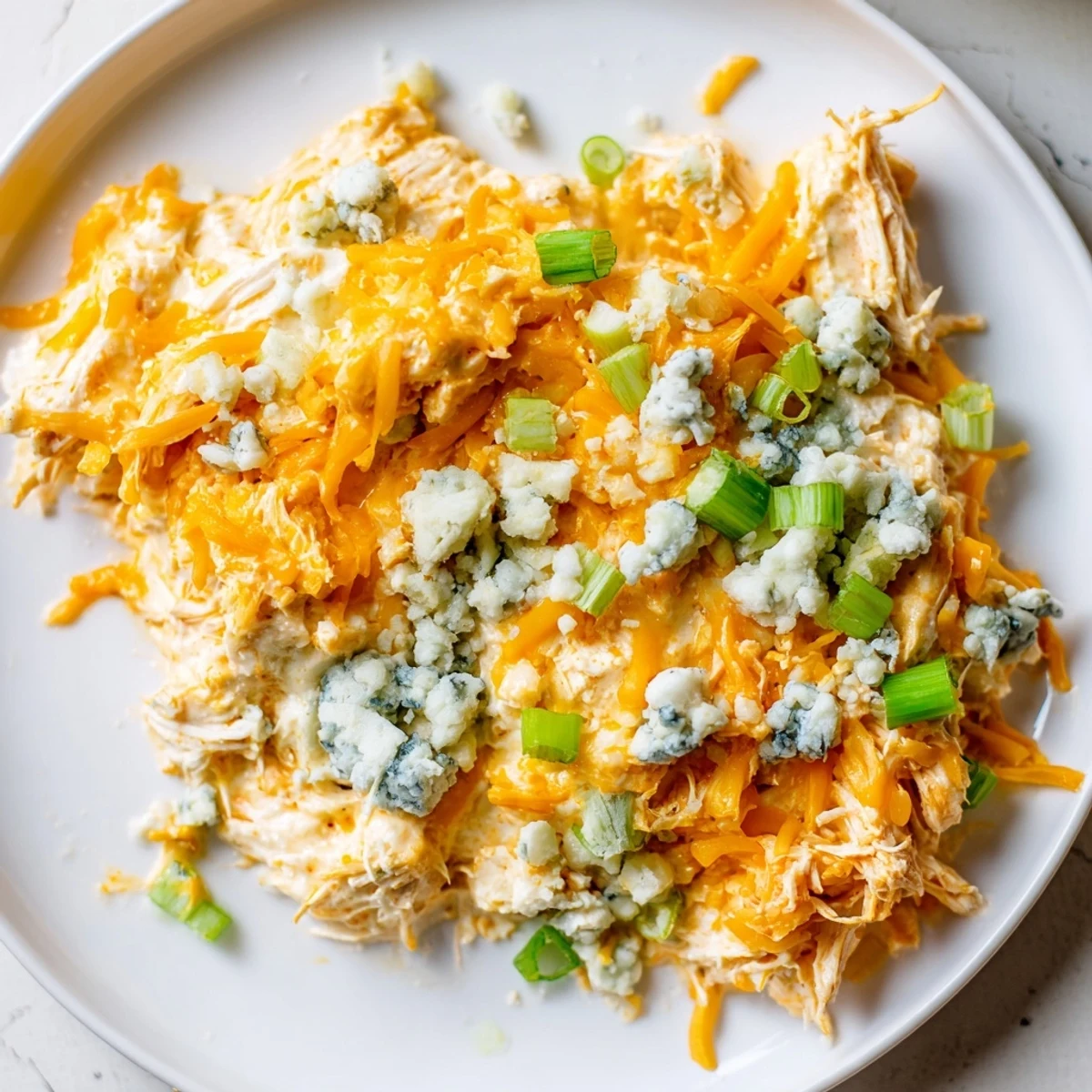 Golden brown Keto Buffalo Chicken Dip served warm from the oven, with cucumber slices and keto-friendly crackers arranged around the dish for game day.