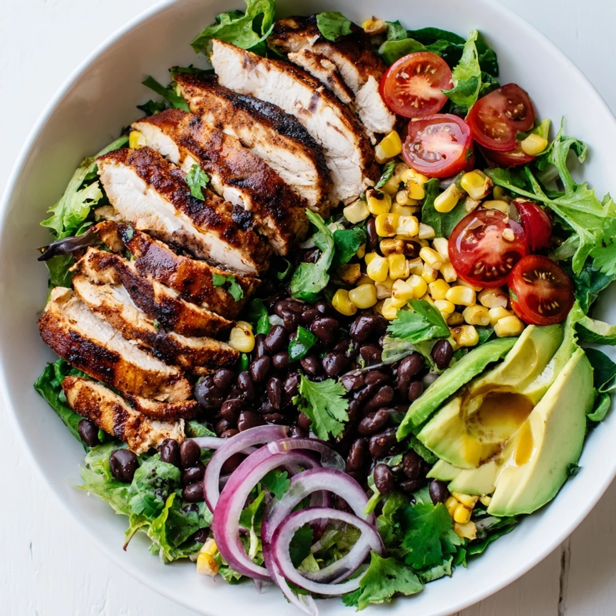 Brightly colored Chipotle Lime Chicken Salad with sliced smoky chicken, fresh avocado, and vibrant cherry tomatoes on a bed of greens.