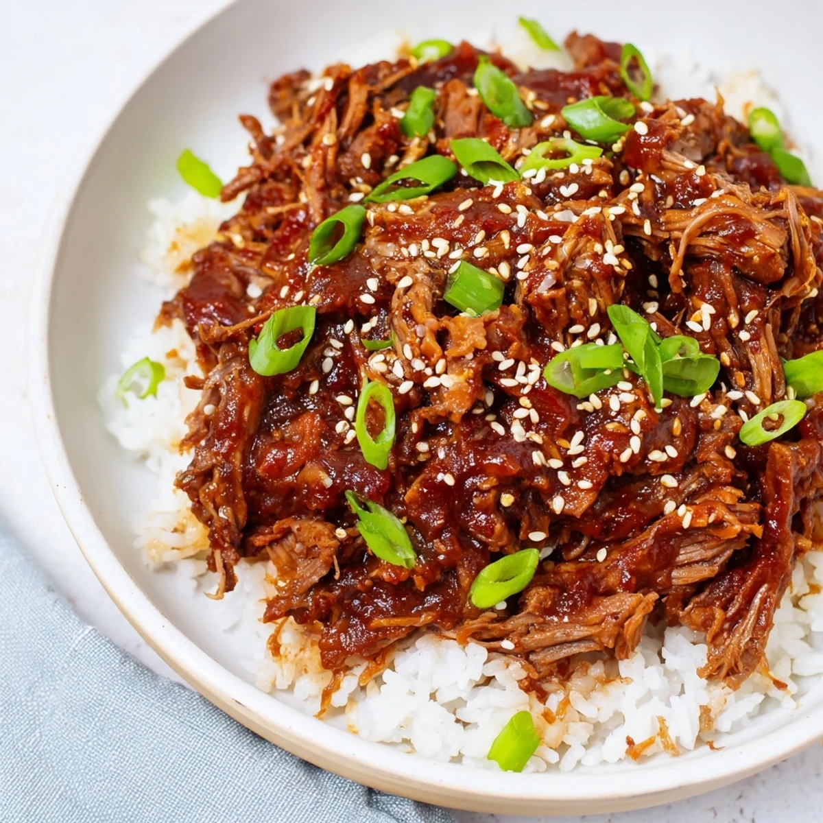 A hearty serving of Crock Pot Korean Beef with glistening sauce and chopped green onions, ready for a comforting meal.