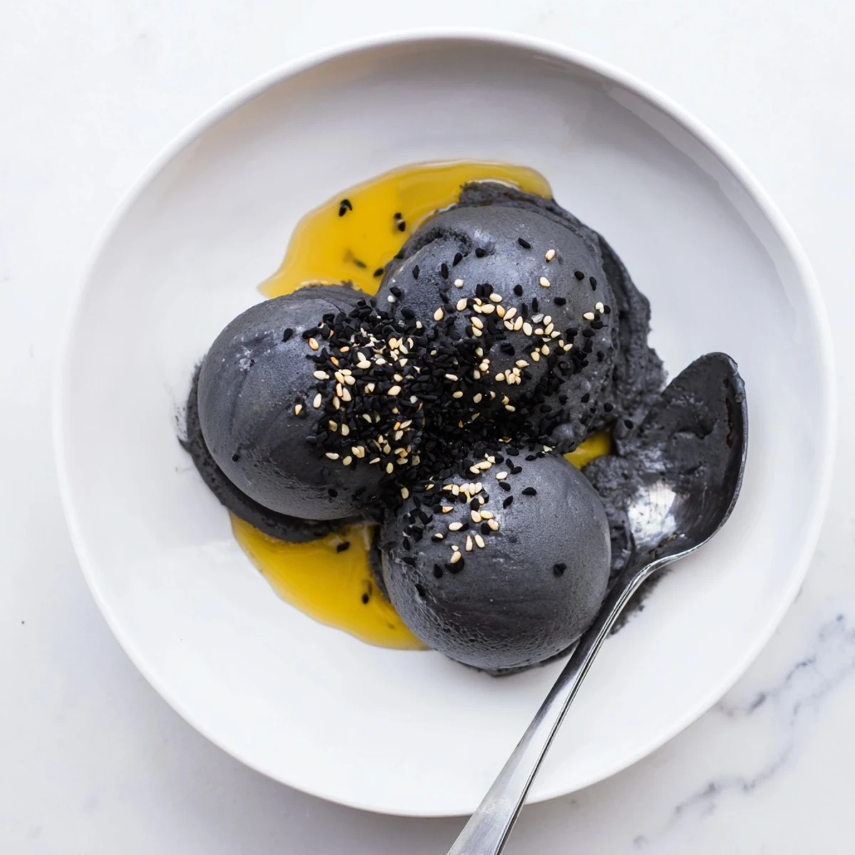 Close-up of creamy Toasted Black Sesame Ice Cream with a velvety gray hue, showing a texture rich with toasted sesame flavor and a glossy finish.