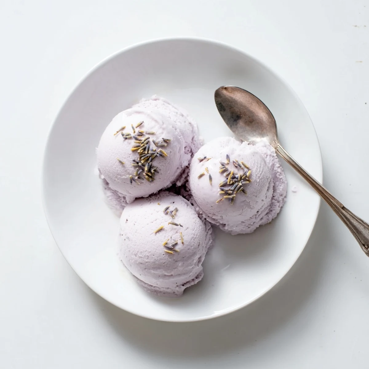 Homemade Lavender Ice Cream served in elegant glassware, garnished with edible flowers for a summer dessert.