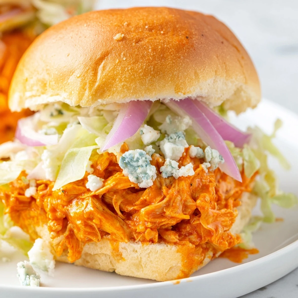 Golden toasted buns hold warm shredded chicken tossed in bold sauce, creating an irresistible handheld meal.