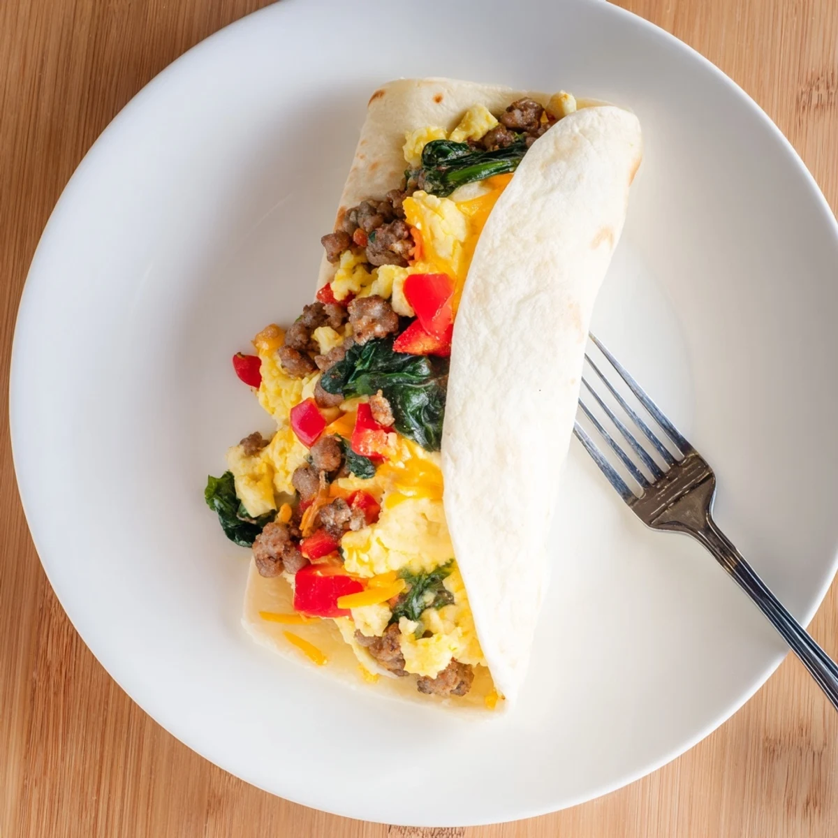 Steaming Make-Ahead Breakfast Burritos plated with fresh salsa, creamy avocado slices, and chopped cilantro.
