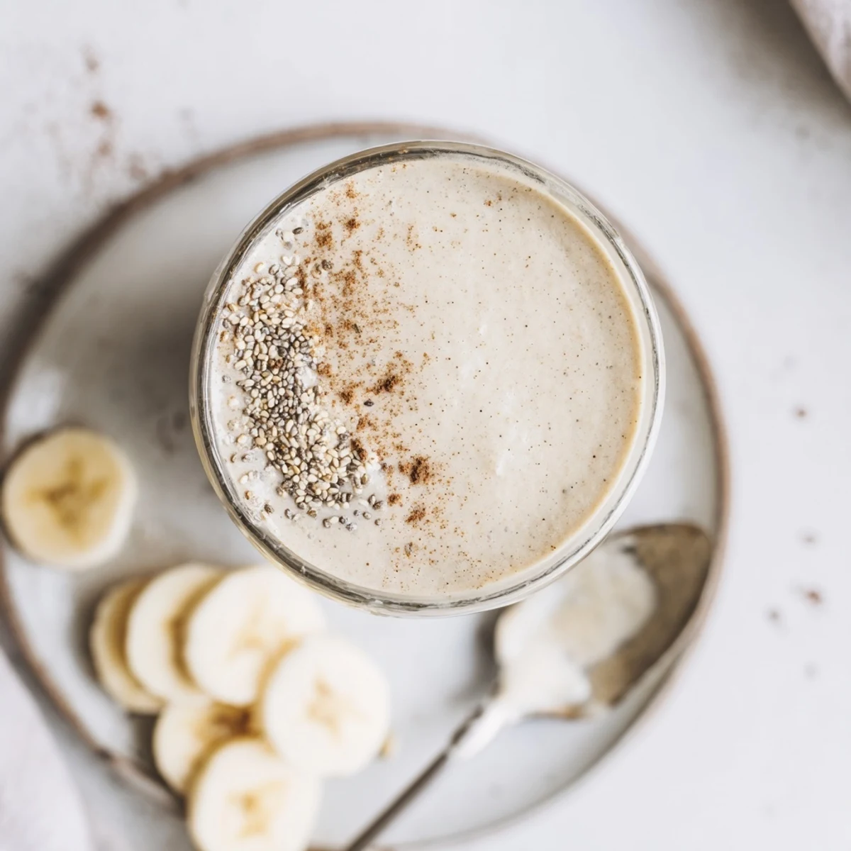 Velvety Greek yogurt banana smoothie topped with cinnamon and chia seeds in glass