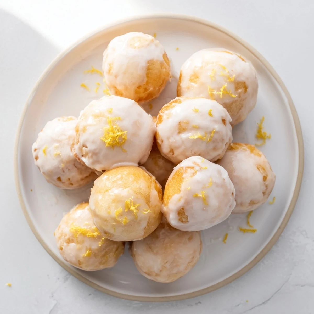 Soft chewy lemon mochi donuts topped with zesty white glaze on wire rack