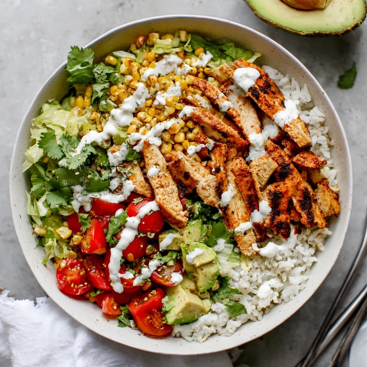 Colorful Mexican-inspired street corn chicken bowl featuring roasted corn kernels avocado slices and tangy white sauce