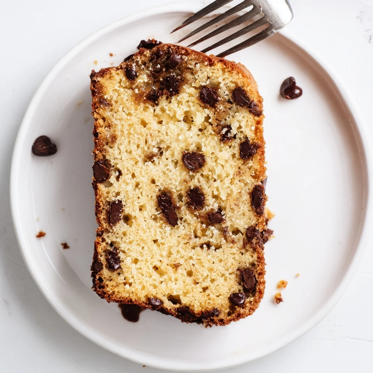 Golden loaf of chocolate chip banana bread with melty chips on top