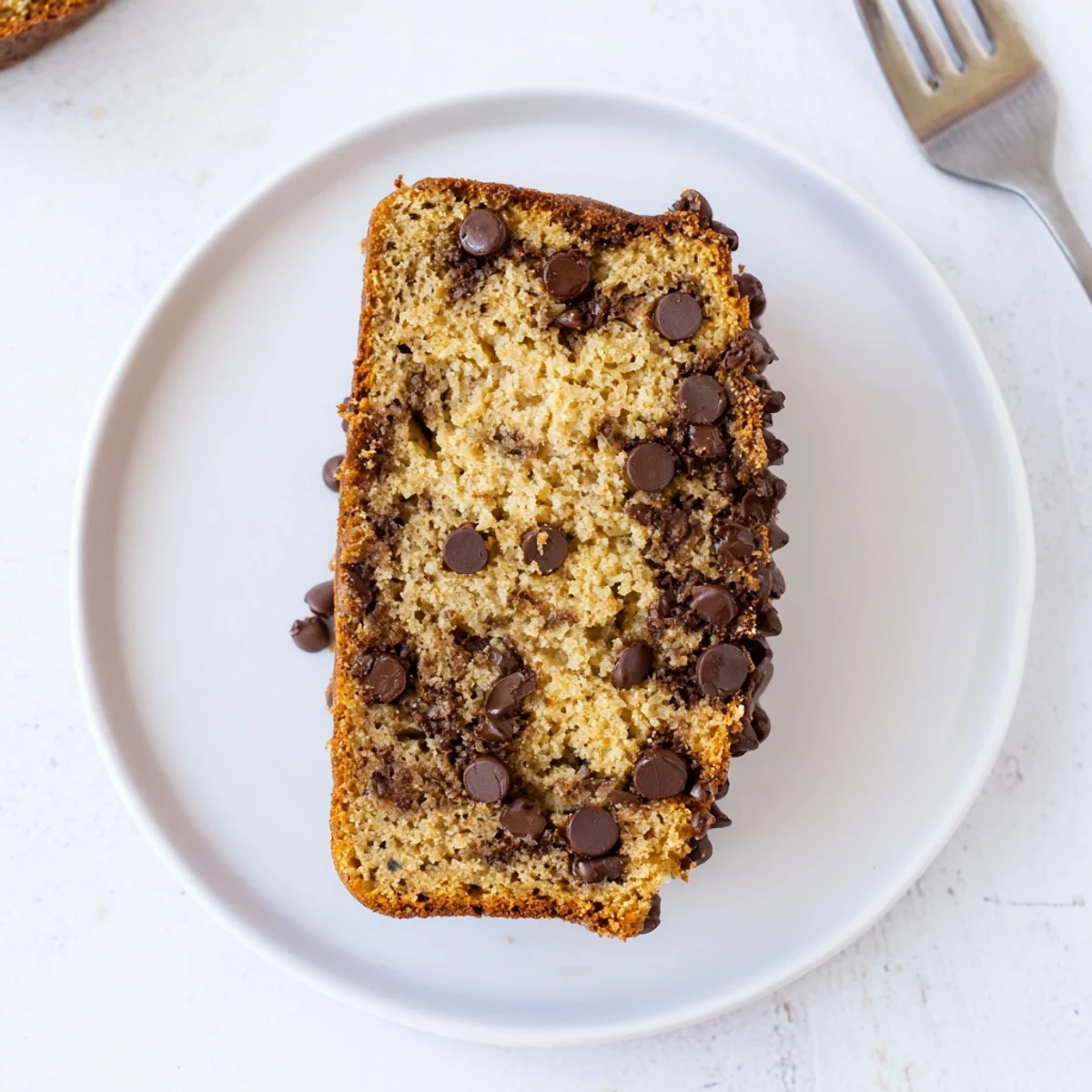 Moist slice of classic chocolate chip banana bread on a white plate