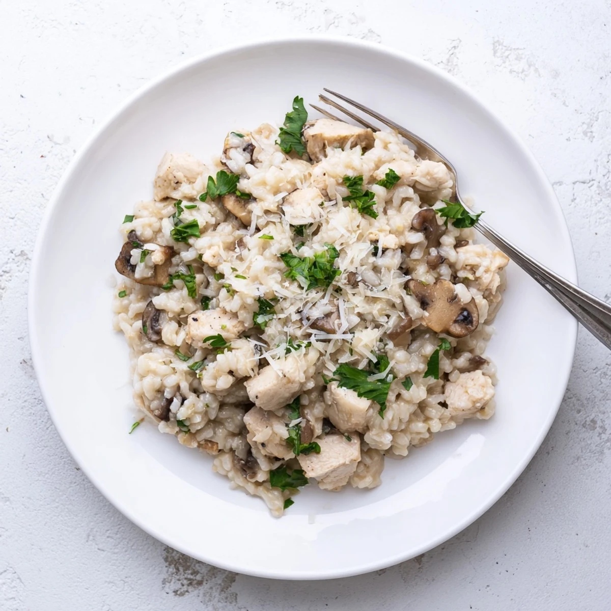 Creamy chicken and mushroom baked risotto garnished with fresh parsley and grated Parmesan cheese