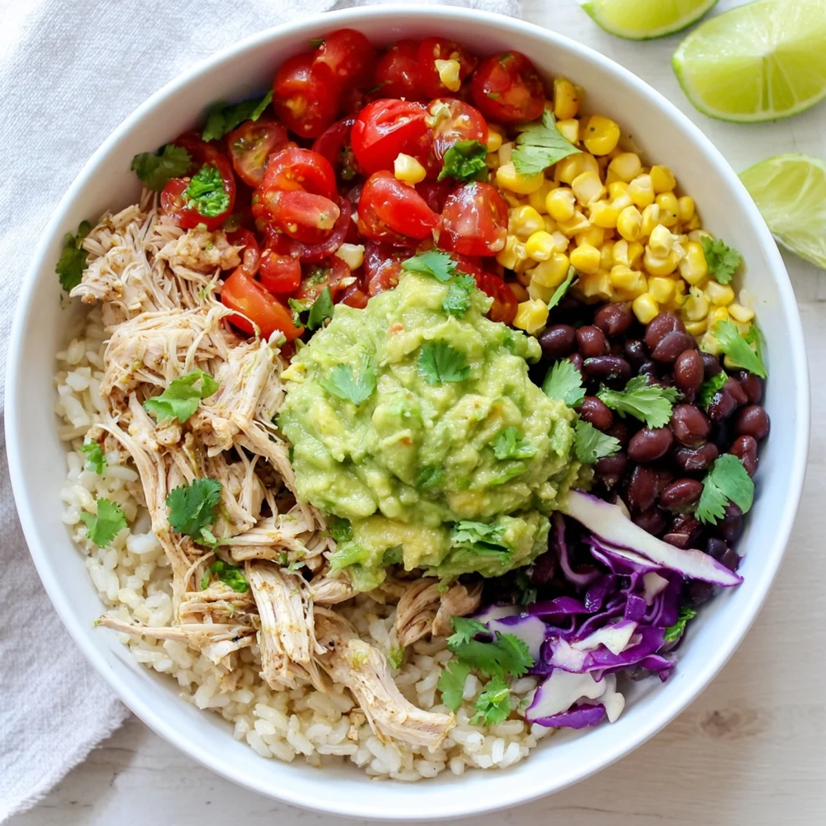 Vibrant Tex-Mex pulled chicken guacamole bowl served over rice with zesty lime wedges
