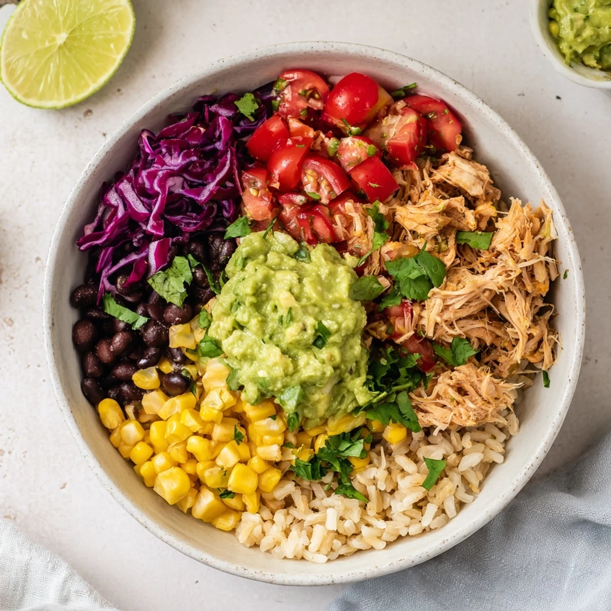Tender shredded chicken nestled in guacamole bowl with black beans crunchy red cabbage