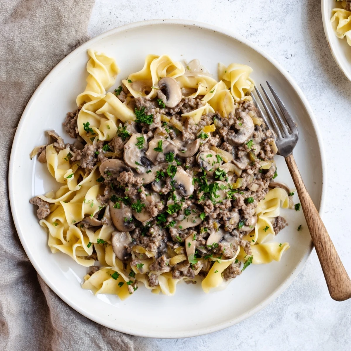 Bowl of rich hamburger stroganoff featuring ground beef and sour cream sauce over noodles