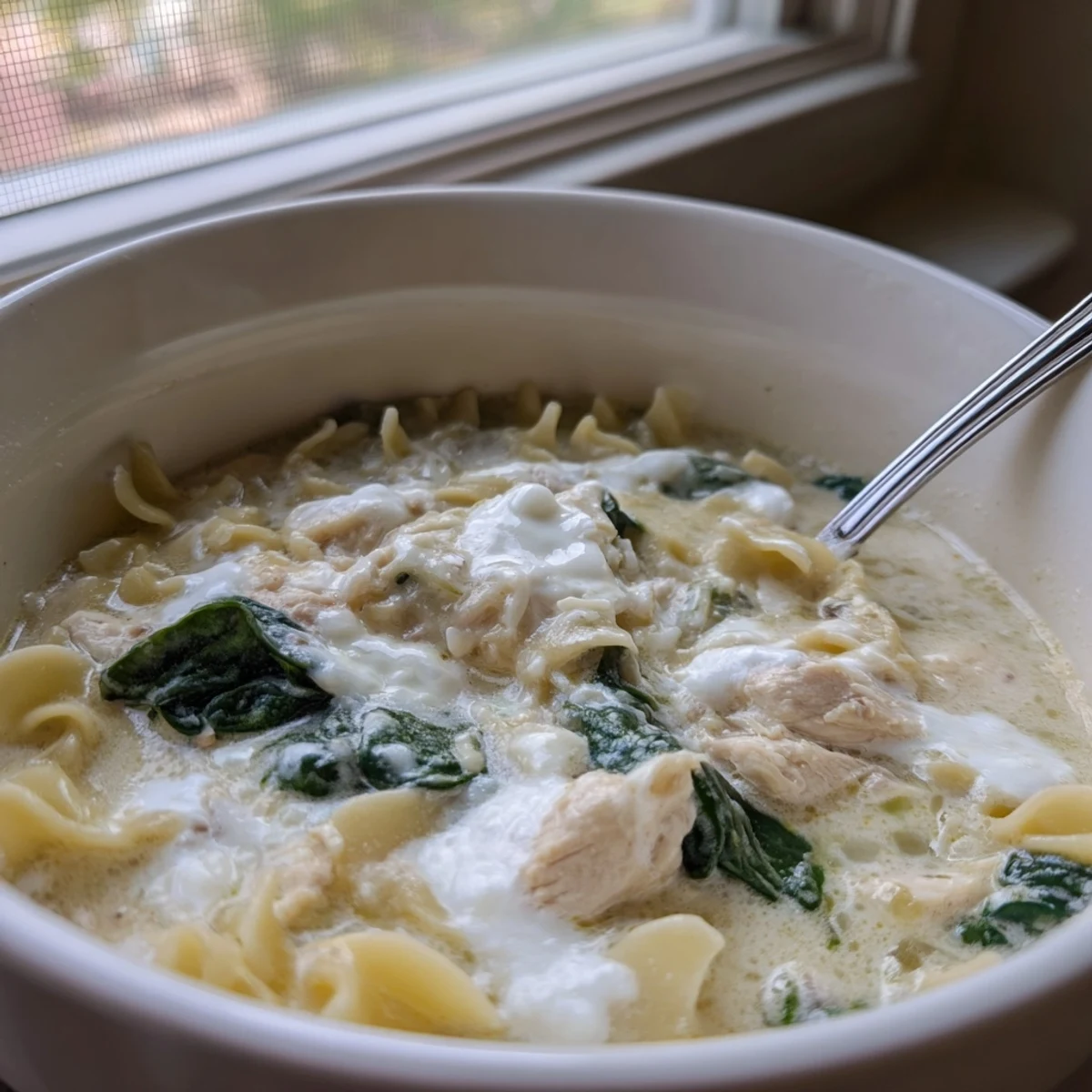 Steaming bowl of white lasagna soup with broken pasta pieces, shredded chicken, and fresh parsley garnish