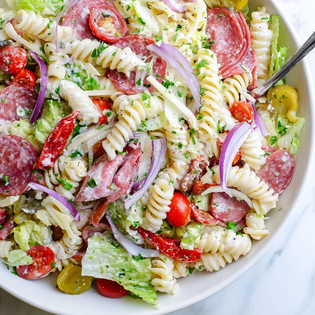 Colorful Italian grinder pasta salad loaded with salami, ham, provolone, and crisp vegetables in a creamy dressing