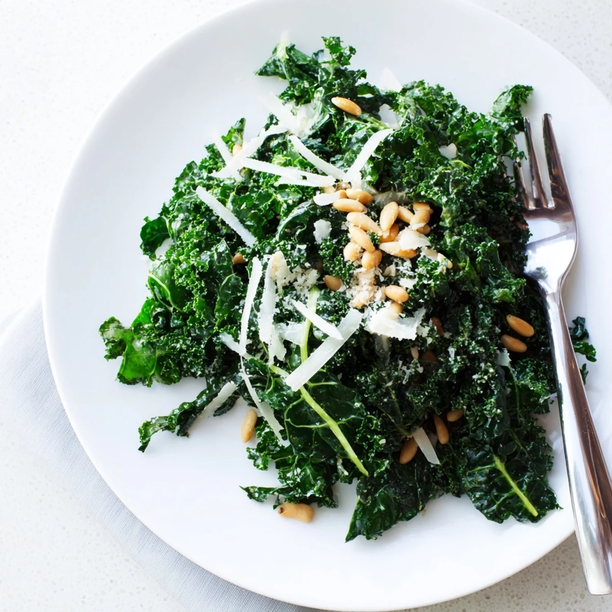 Crisp garlic lemon Parmesan kale salad topped with toasted pine nuts and cheese