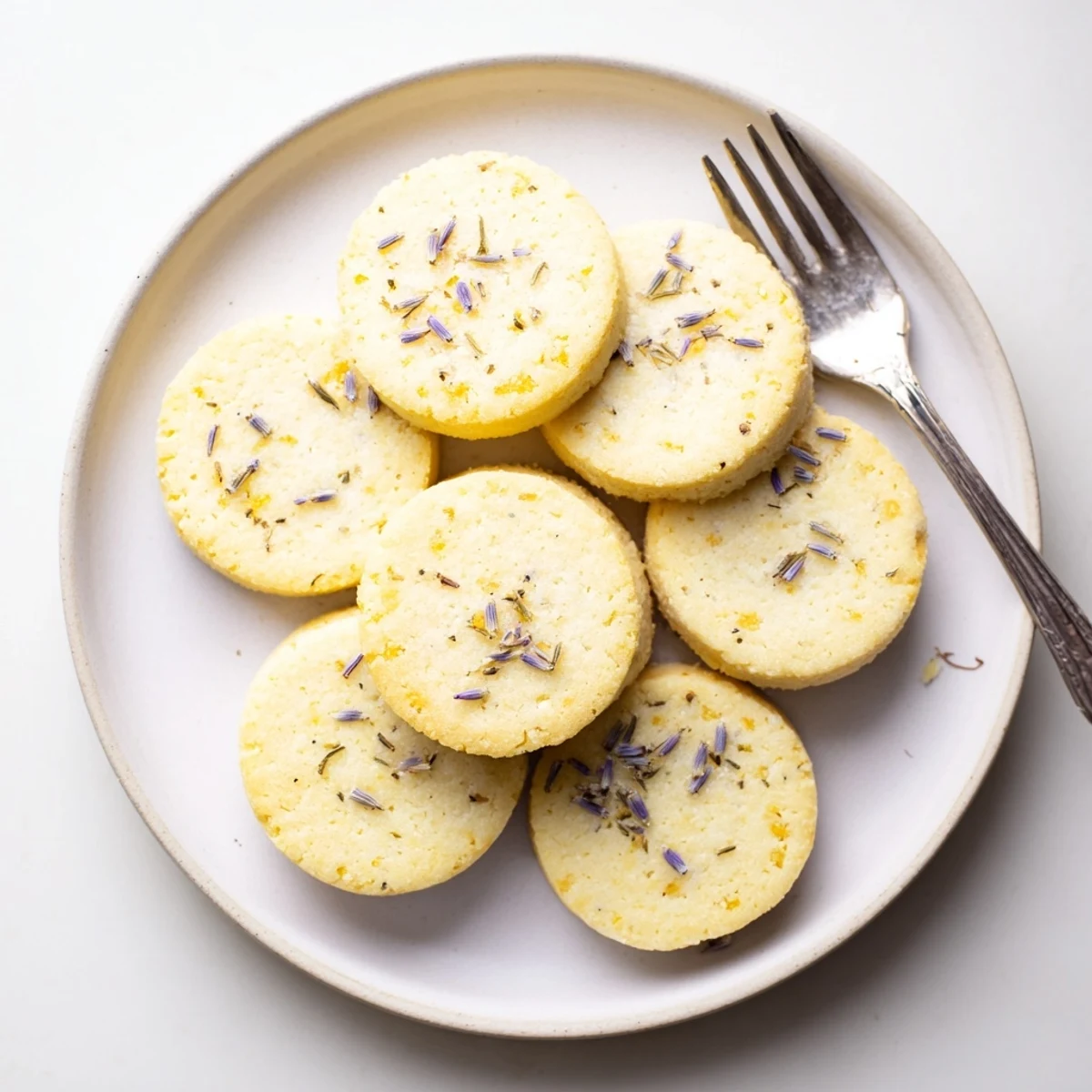 Golden Lemon Lavender Cookies arranged on a rustic wooden board with tea cup nearby