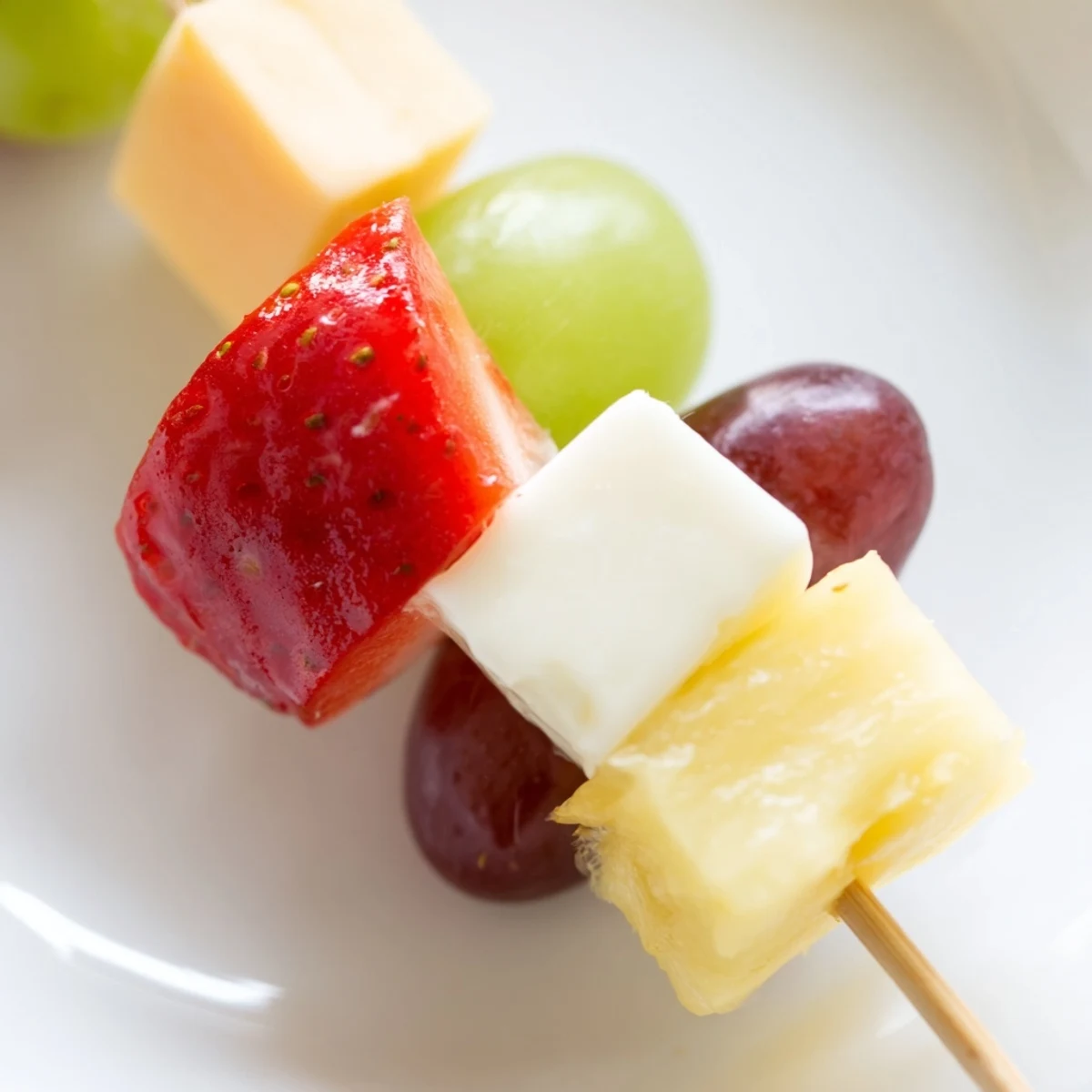 Fresh fruit and cheese kabobs featuring alternating cubes of creamy mozzarella juicy grapes and sweet pineapple chunks