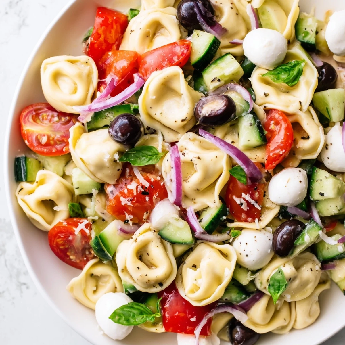 Cheese tortellini salad featuring ripe cherry tomatoes, diced cucumber, and zesty herb vinaigrette