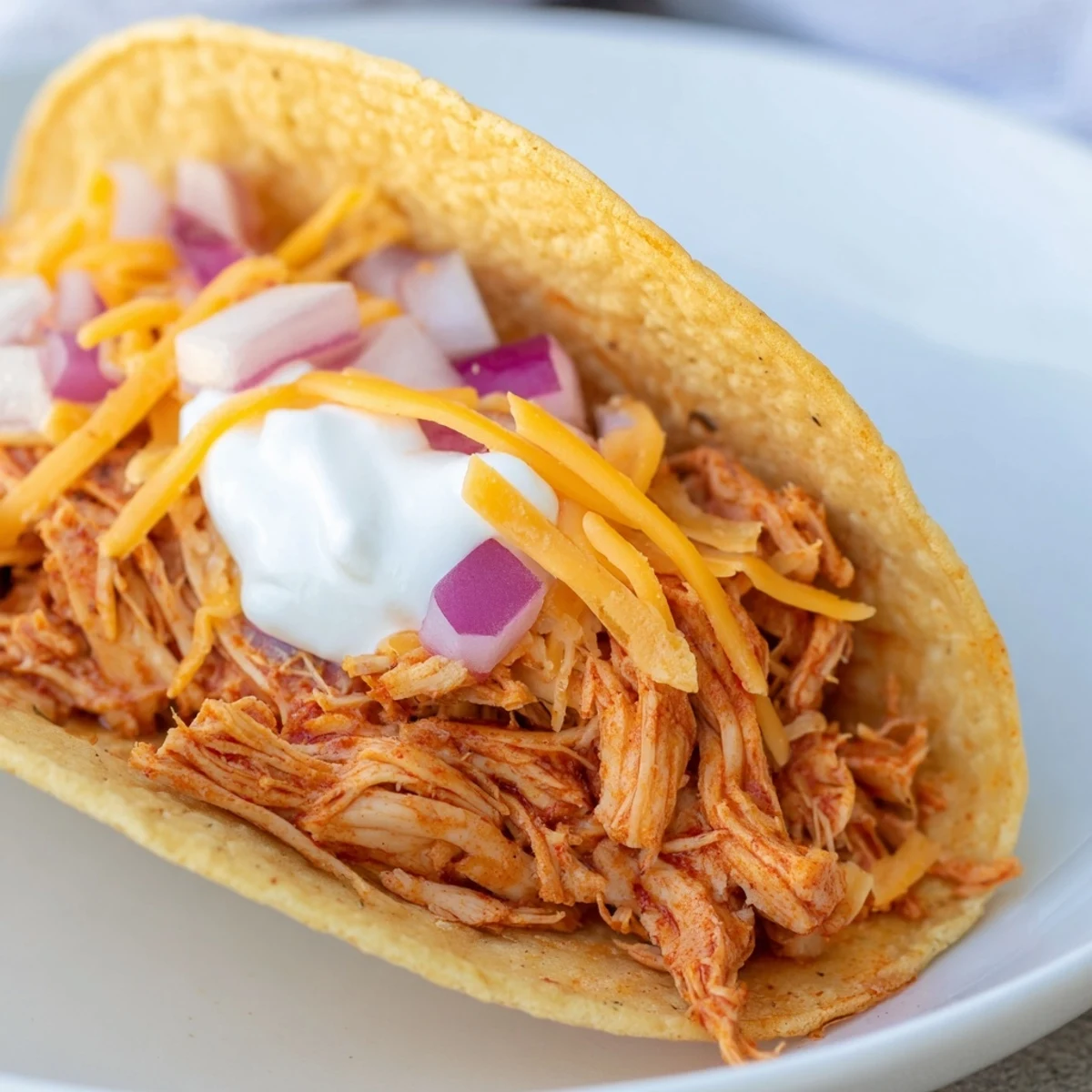 Juicy slow cooker shredded chicken tacos loaded with cheese, lettuce, and fresh cilantro in crispy shells