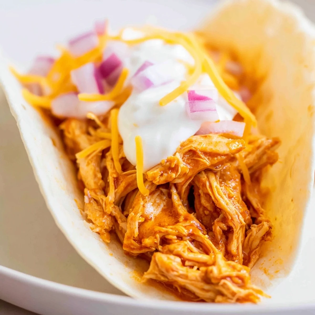 Tender slow cooker shredded chicken tacos topped with sour cream, avocado, and diced tomatoes